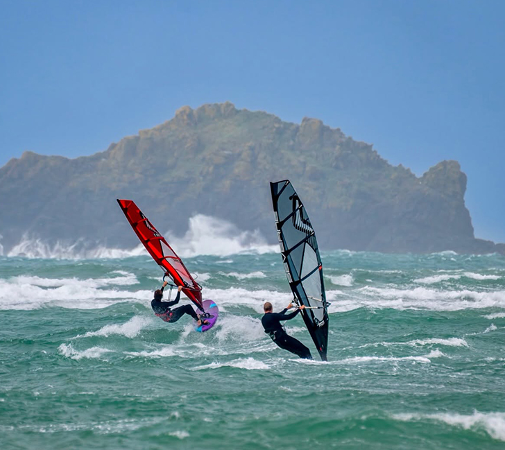 Windsurfers gliding over the sea with waves and coastal scenery