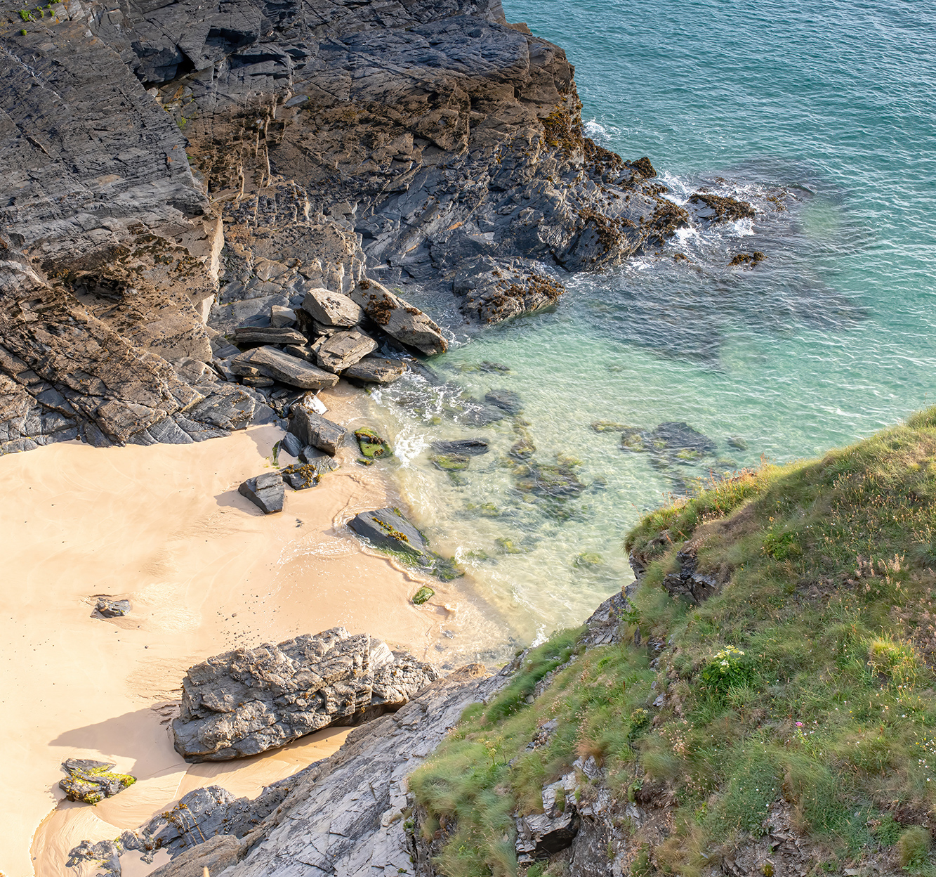 Hidden coves along the north Cornwall coast with rocky cliffs and clear blue sea