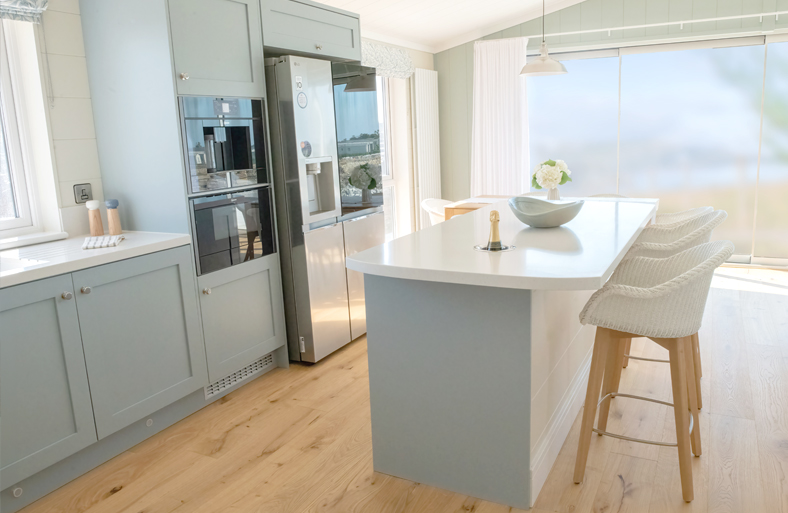 Open-plan kitchen with panoramic windows framing views of the large pond.