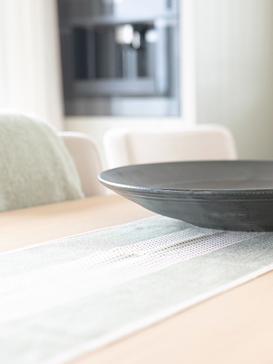 Dining table featuring a linen runner, ceramic tableware and contemporary coastal styling.