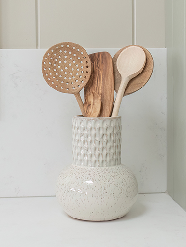 Wooden serving utensils displayed in a beautifully textured ceramic vase.