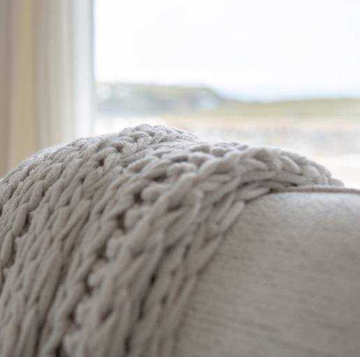 Armchair with a soft chunky knitted throw positioned to enjoy views over Mother Ivey's Bay.